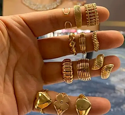 Altın yüzüklerle süslenmiş bir kişinin eli.